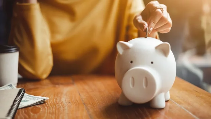 Someone is putting money into a piggy bank | Jemand steckt Münzen in ein Sparschwein rein